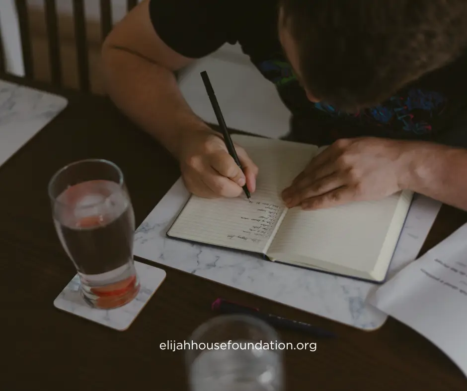 overhead view of a man intently writing in a journal